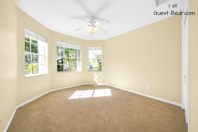 empty room with light carpet, ceiling fan, and a wealth of natural light