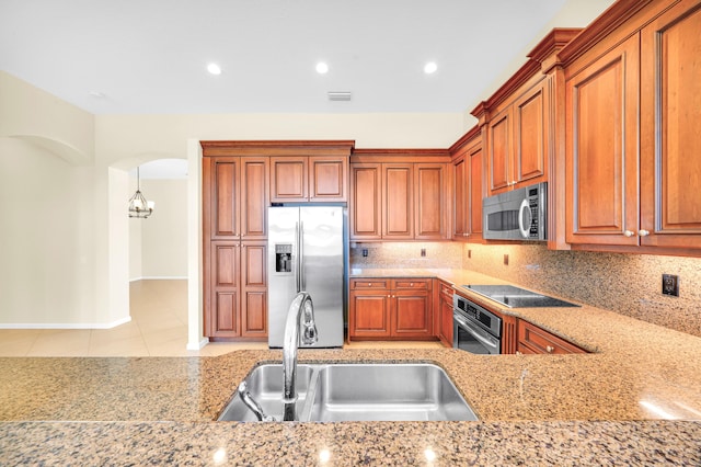 kitchen featuring light stone countertops, an inviting chandelier, appliances with stainless steel finishes, sink, and tasteful backsplash