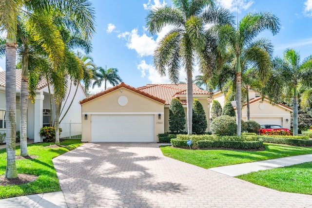 mediterranean / spanish home featuring a front yard and a garage