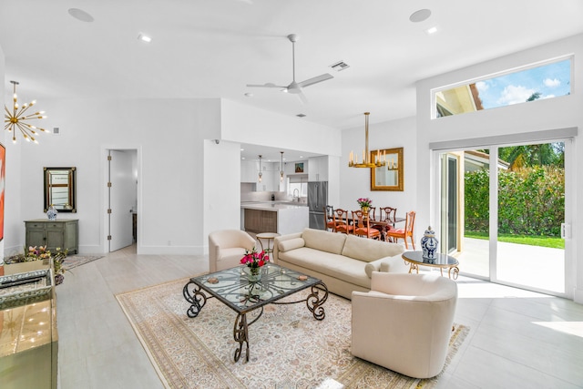 tiled living room featuring a towering ceiling and ceiling fan with notable chandelier