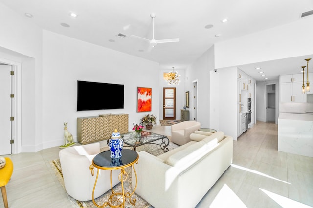 tiled living room with ceiling fan with notable chandelier