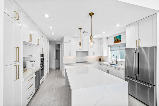 kitchen with pendant lighting, sink, appliances with stainless steel finishes, white cabinetry, and a center island