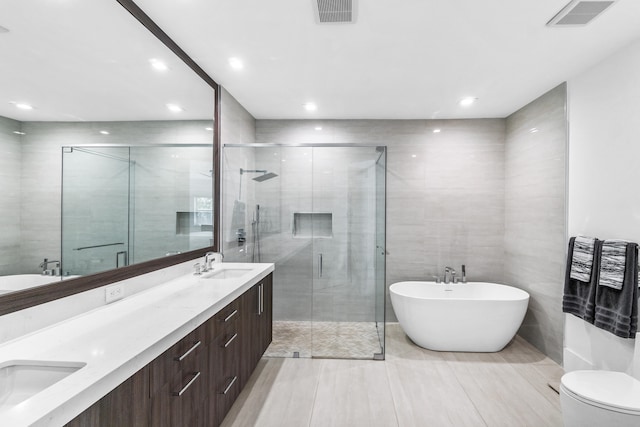 full bathroom featuring tile flooring, large vanity, dual sinks, and tile walls