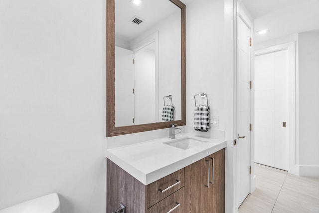 bathroom with toilet, tile flooring, and vanity