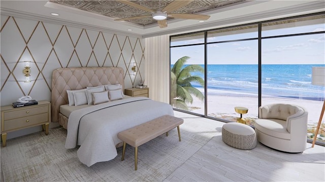 bedroom featuring light wood-type flooring, multiple windows, and a water view