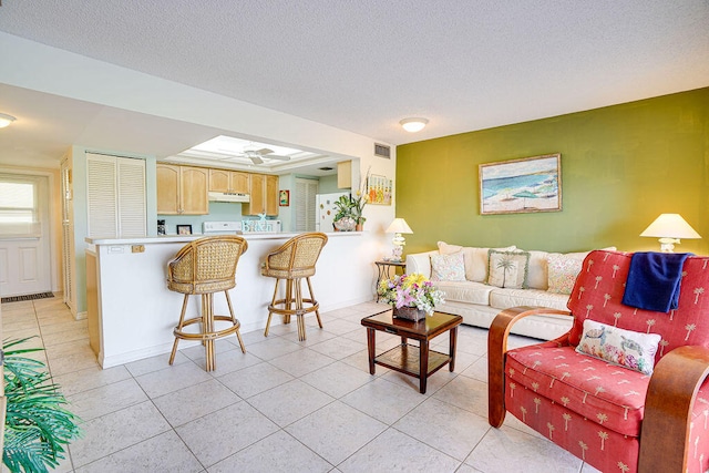 living room with light tile floors, ceiling fan, and a textured ceiling