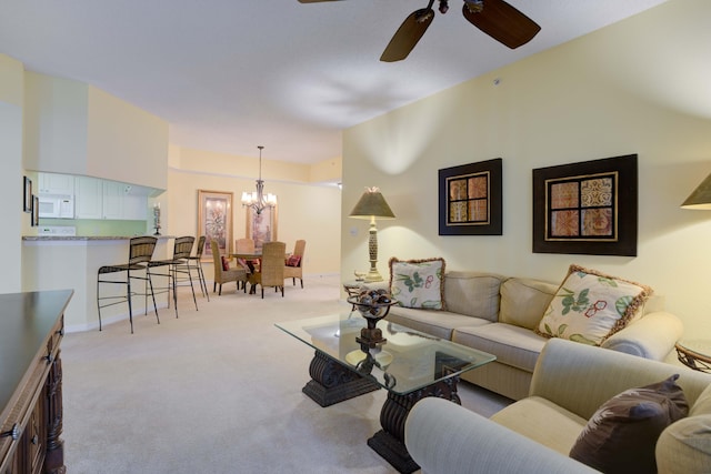 living room featuring light carpet and ceiling fan with notable chandelier