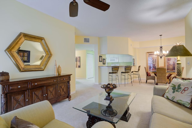 living room with ceiling fan with notable chandelier and light colored carpet