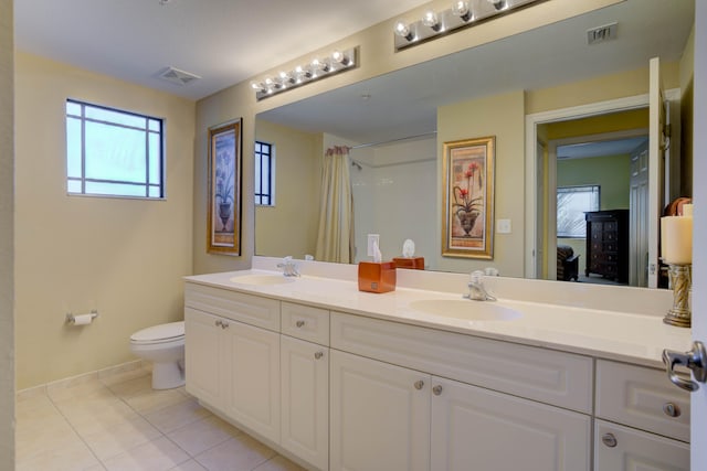 bathroom with toilet, large vanity, double sink, and tile flooring