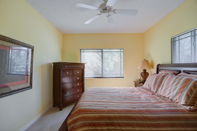 bedroom with light carpet, multiple windows, ceiling fan, and a textured ceiling