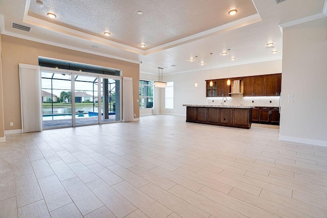 unfurnished living room featuring light hardwood / wood-style floors, crown molding, a raised ceiling, and a textured ceiling