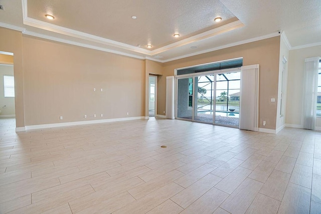 empty room with ornamental molding, a raised ceiling, a textured ceiling, and a wealth of natural light