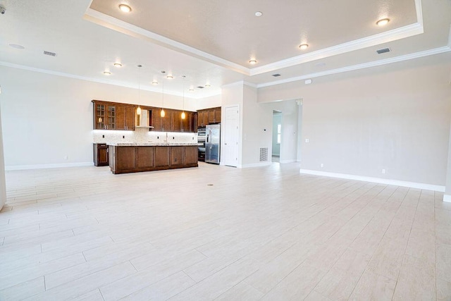 unfurnished living room with light hardwood / wood-style floors, crown molding, and a raised ceiling