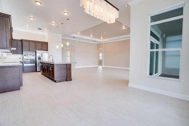 kitchen featuring dark brown cabinets, light stone countertops, crown molding, stainless steel fridge, and a kitchen island with sink