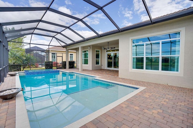 view of swimming pool with a patio, glass enclosure, and ceiling fan