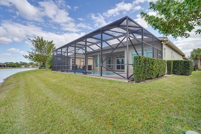 rear view of property with a water view, glass enclosure, a patio area, and a yard