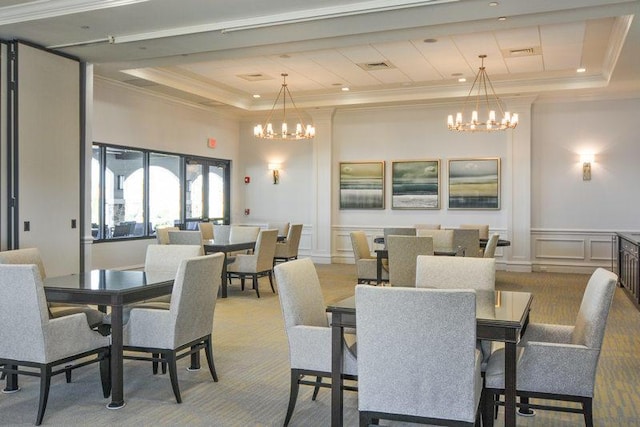 carpeted dining room with a tray ceiling, ornamental molding, and a notable chandelier