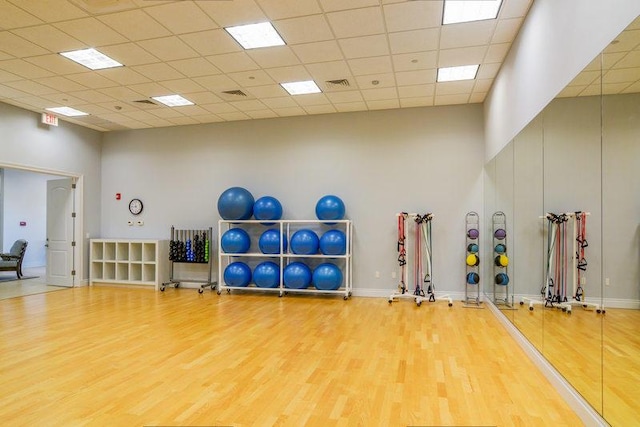 exercise room with hardwood / wood-style floors, a paneled ceiling, and a towering ceiling