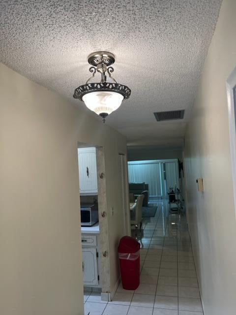 hall with light tile floors and a textured ceiling