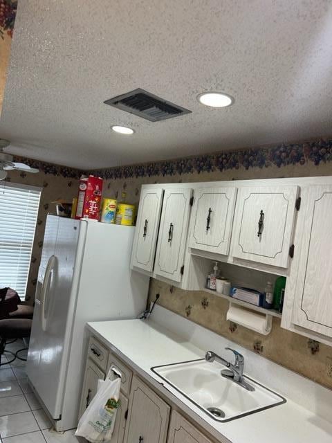 kitchen with ceiling fan, sink, light tile floors, a textured ceiling, and white cabinetry