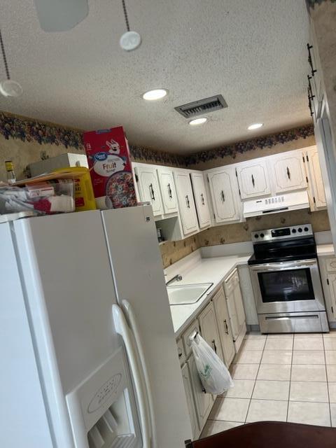 kitchen with white appliances, sink, light tile floors, white cabinets, and a textured ceiling