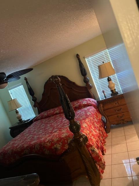 bedroom with a textured ceiling and light tile floors