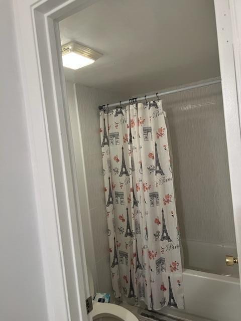 bathroom featuring shower / bath combination with curtain and toilet