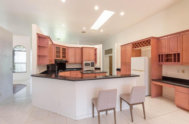 kitchen with built in desk, stainless steel appliances, kitchen peninsula, and light tile patterned flooring