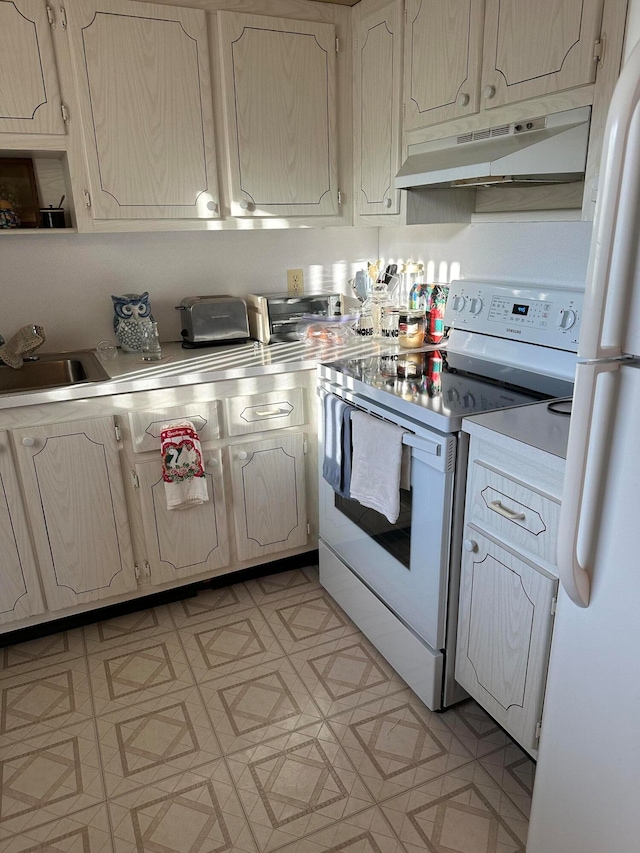 kitchen featuring stove, sink, and white fridge