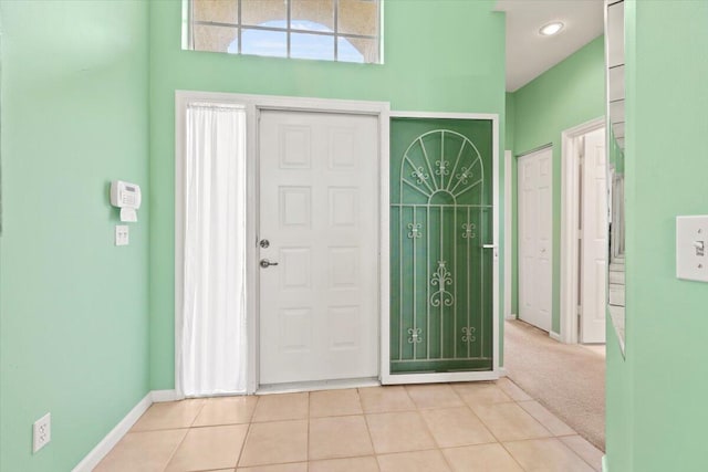 foyer entrance with light carpet and a towering ceiling