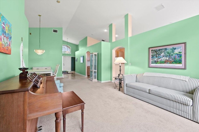 carpeted living room featuring an inviting chandelier and high vaulted ceiling