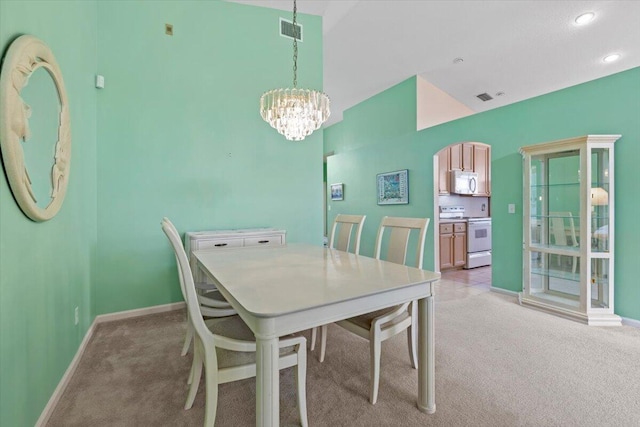 carpeted dining room featuring an inviting chandelier and high vaulted ceiling