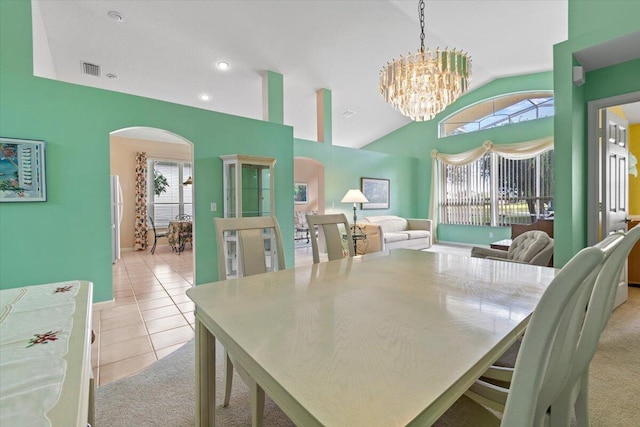 tiled dining room with plenty of natural light, a chandelier, and high vaulted ceiling