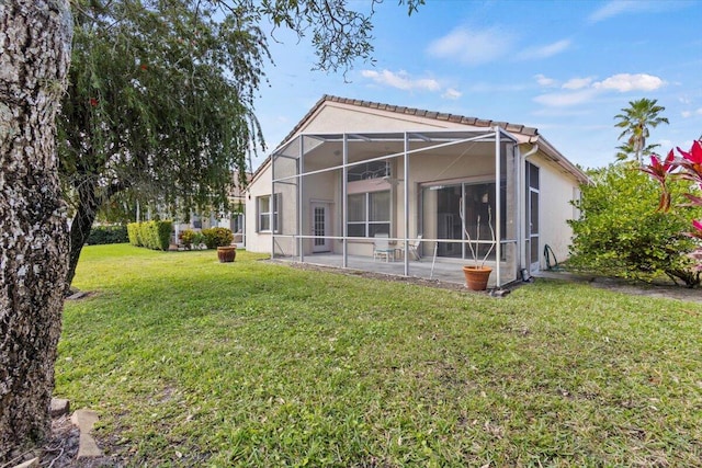 rear view of property featuring a yard, a patio, and a lanai