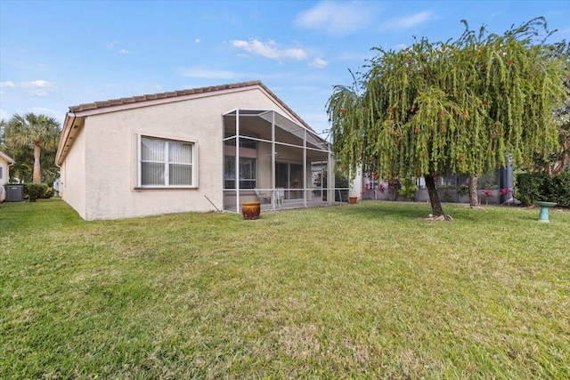 back of property with a lawn and glass enclosure