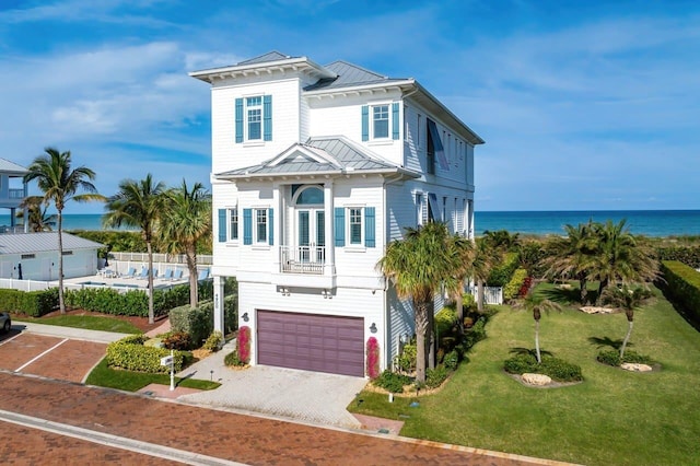 view of front of home featuring a water view, a garage, and a front lawn