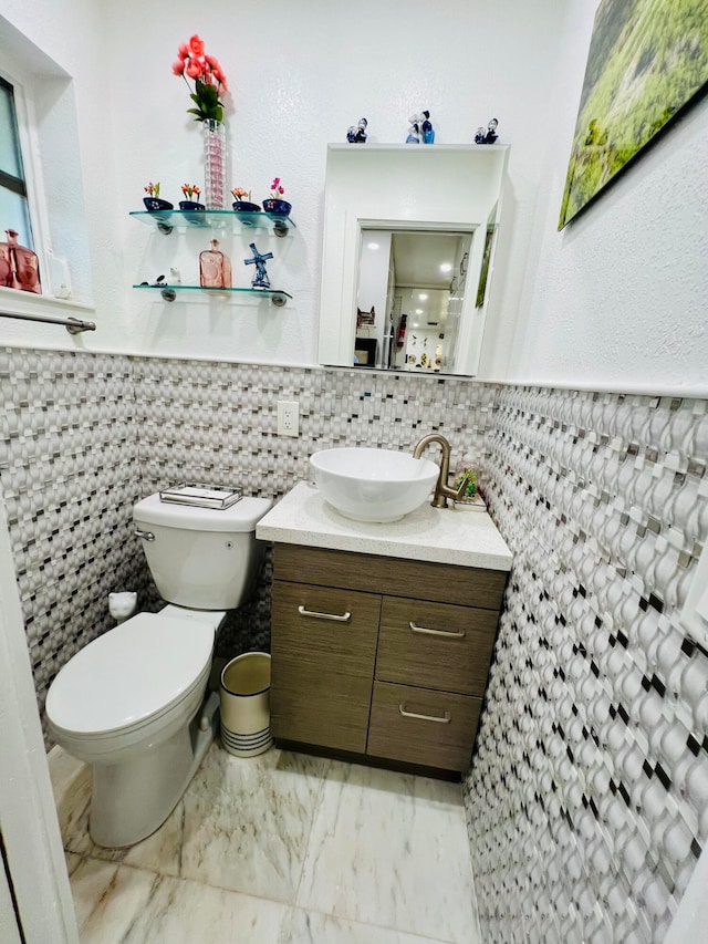 bathroom with tile walls, toilet, vanity with extensive cabinet space, backsplash, and tile flooring