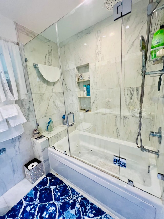 bathroom featuring tile walls and bath / shower combo with glass door