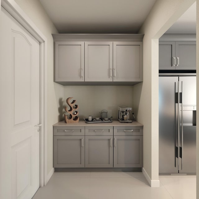 bar featuring gray cabinetry, light tile flooring, and stainless steel fridge with ice dispenser