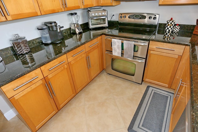 kitchen featuring stainless steel electric stove, light tile flooring, and dark stone counters