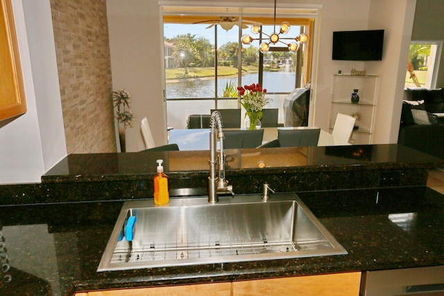 kitchen featuring dark stone countertops, sink, a healthy amount of sunlight, and a water view