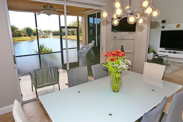 dining area featuring a water view, light tile floors, and ceiling fan with notable chandelier