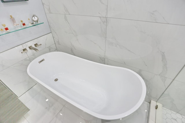 bathroom with tile walls, a tub, and tile flooring