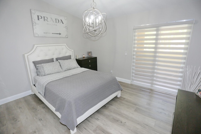 bedroom with a chandelier, vaulted ceiling, and light hardwood / wood-style floors