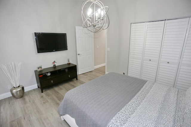 bedroom with light hardwood / wood-style floors, a closet, and an inviting chandelier