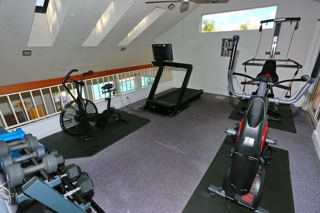 exercise room featuring a textured ceiling, ceiling fan, and lofted ceiling