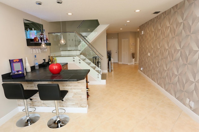 interior space featuring light tile flooring, a kitchen bar, tile counters, and kitchen peninsula