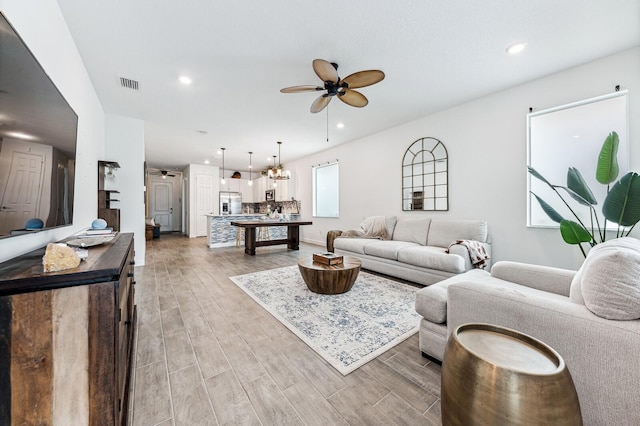 living room featuring light hardwood / wood-style flooring and ceiling fan with notable chandelier