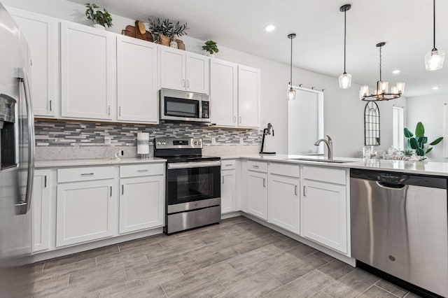 kitchen featuring hanging light fixtures, an inviting chandelier, sink, stainless steel appliances, and white cabinets