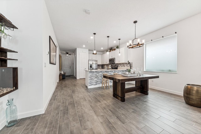 kitchen with tasteful backsplash, hanging light fixtures, stainless steel appliances, an inviting chandelier, and white cabinetry